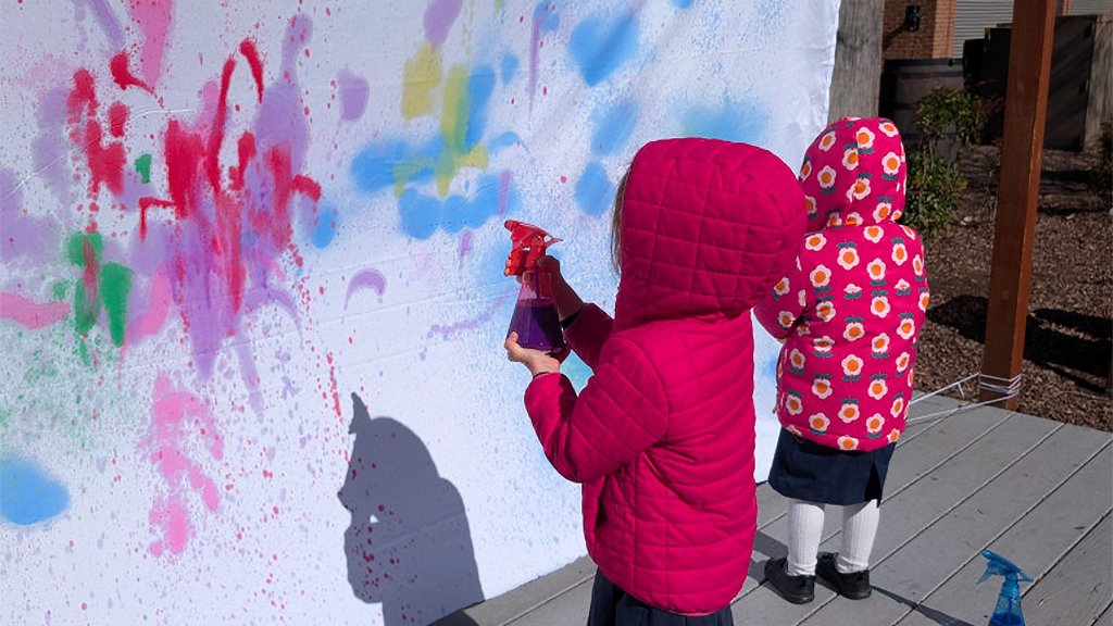Elementary students painting with a spray bottle