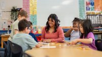 Elementary teacher working with a small group of students on a writing assignment