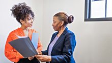 An administrator delegating work to another staff member in a school hallway
