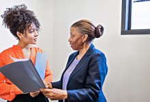An administrator delegating work to another staff member in a school hallway