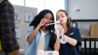 Two high school students working on a wind turbine project