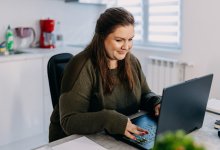 New teacher working at a laptop on engaging onboarding modules in her kitchen