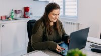 New teacher working at a laptop on engaging onboarding modules in her kitchen