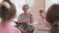 Elementary teacher reading a book to students