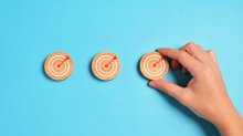 A hand setting up small wooden targets