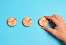 A hand setting up small wooden targets