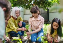 A teacher guiding a gardening club as they plant outdoors