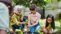 A teacher guiding a gardening club as they plant outdoors