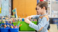 A child looking through a book bin in a classroom