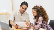 Teacher working 1:1 on a paper with middle or high school student