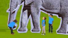 Elementary students looking at a life-size paper model of an elephant