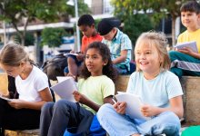 Elementary students sitting outdoors with notebooks and observing their surroundings