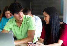 Two high school students working together on a laptop
