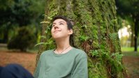 A high school student observing nature while sitting underneath a tree