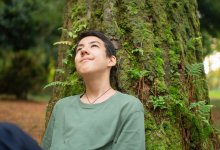 A high school student observing nature while sitting underneath a tree