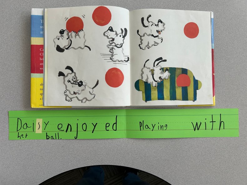 A student's written sentence based on a page from a wordless picture book