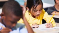 Elementary students drawing at their desks