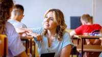 A teacher kneeling and talking calmly to a middle school student