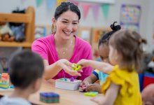 A teacher passing a preschool student a toy