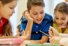 A small group of elementary students examining materials on their table curiously