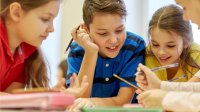 A small group of elementary students examining materials on their table curiously