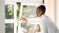 A teacher opening up a window in his classroom