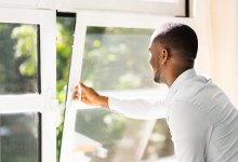 A teacher opening up a window in his classroom
