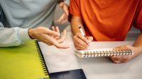 A teacher guiding a male middle school student through journaling practices