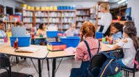 Elementary students sitting with art supplies in a school library