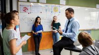 A teacher guiding high school students through a science-based skit