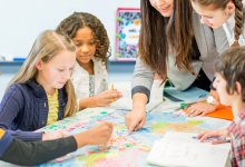 A group of students watching intently as their teacher points to sections on a map
