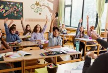 Elementary students raising their hands in response to their teacher