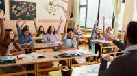 Elementary students raising their hands in response to their teacher