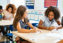 Elementary students smiling and talking to the students sitting around them