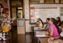 Middle school teacher reading book in front of the class