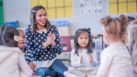 Preschool teacher leading students in a clapping exercise