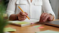 Adult making notes in a journal with sticky notes