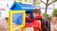 Child looking through books in a community free library