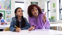 Teacher working with student at her desk