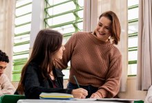 A teacher making conversation with one of her students at their desk