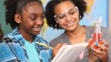 Two students recording the results of a science experiment in a notebook