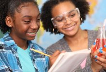Two students recording the results of a science experiment in a notebook
