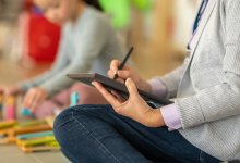 Teacher taking notes on a tablet while observing student