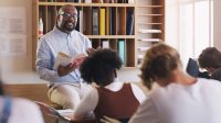 A high school teacher lecturing his students on a book