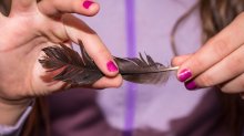 A student carefully holding a bird feather