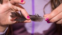 A student carefully holding a bird feather