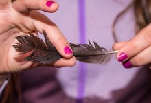 A student carefully holding a bird feather