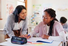 Middle school teacher working with student at her desk