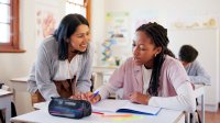 Middle school teacher working with student at her desk