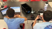 Two middle school students coding and building a car
